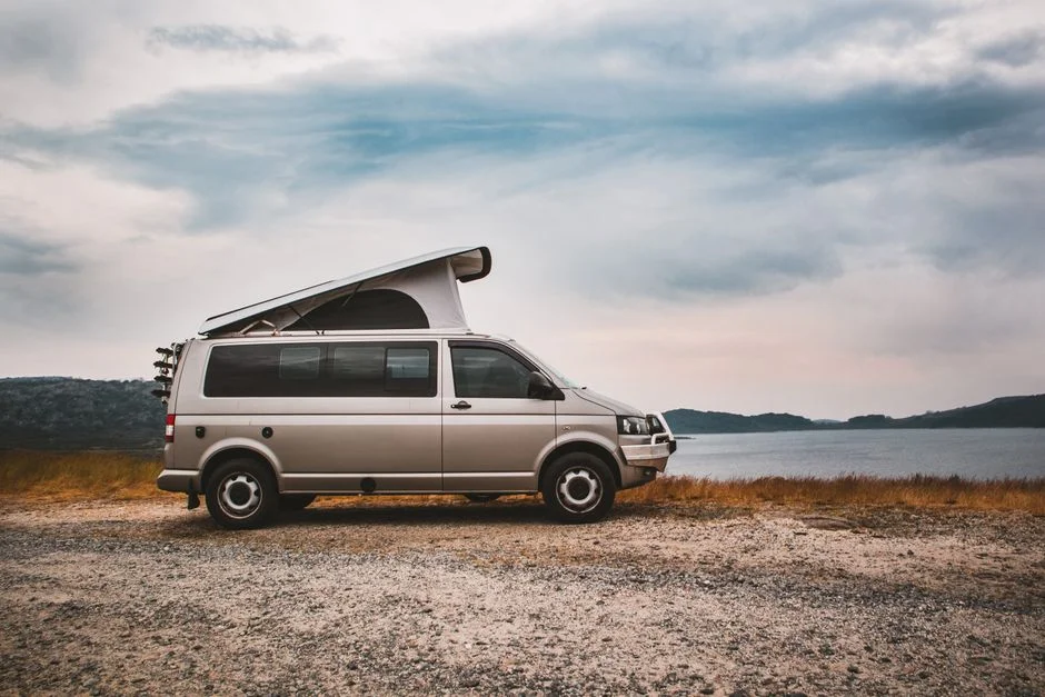 VW Bus Camper mit aufgestelltem Aufstelldach an einem See
