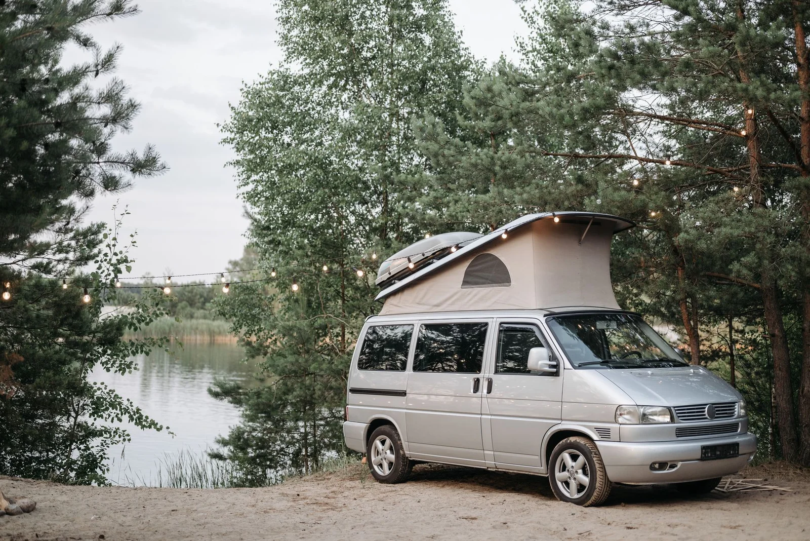 VW Campingvan mit geöffnetem Aufstelldach von der Seite an einem See